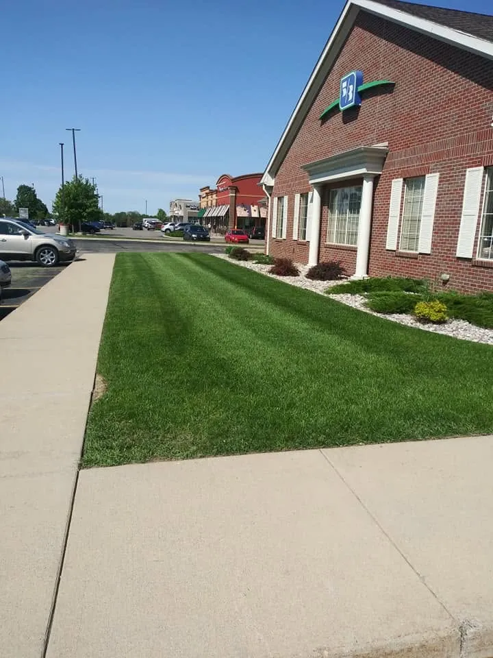Striped lawn maintained by Oasis in front of a brick bank building on a Kalamazoo commercial strip