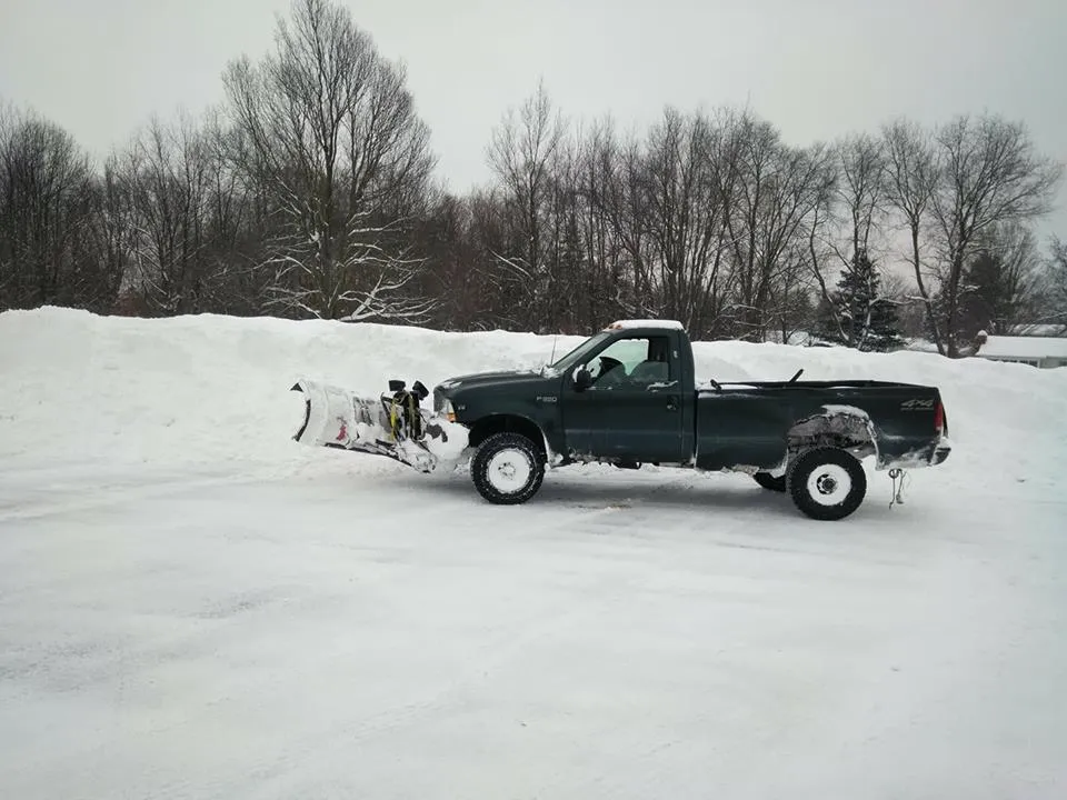 Oasis plow truck in a cleared parking lot with snow piled high along the edges