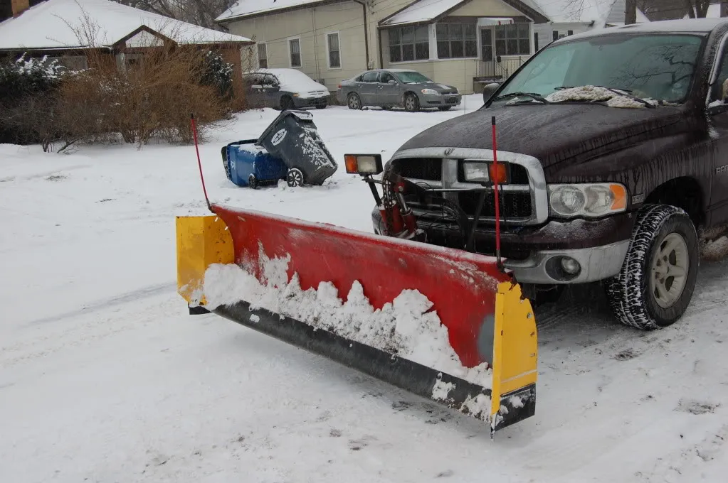 Close view of a plow blade carrying snow on a residential street